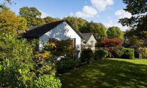 ein weißes Haus in einem Garten mit grünem Rasen in der Unterkunft Merewood Lodge in Ambleside