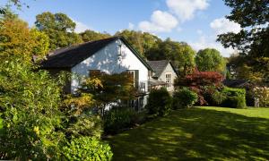 a white house in a yard with a green lawn at Merewood Lodge in Ambleside
