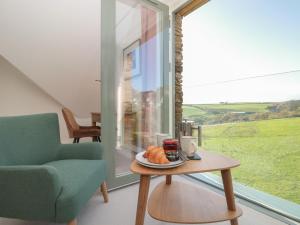 a living room with a table and a chair and a window at 4 Court Terrace, Hillfield Village in Dartmouth