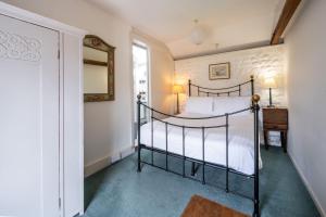 een slaapkamer met een bed, een spiegel en een raam bij Lifeboat Cottage by Big Skies Cottages in Brancaster