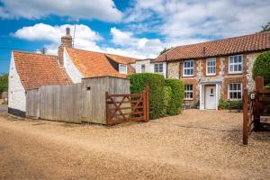 a house with a wooden gate and a fence at Lifeboat Cottage by Big Skies Cottages in Brancaster