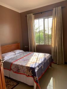 a bedroom with a bed and a large window at Dodoma, Tukae Inn in Dodoma