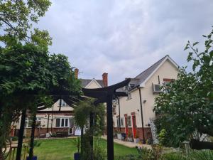 a house with a pergola in the front yard at Peaceful self contained Studio in lovely garden. in Hinckley