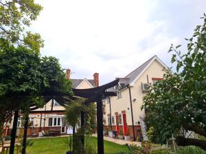 a house with a pergola in the front yard at Peaceful self contained Studio in lovely garden. in Hinckley