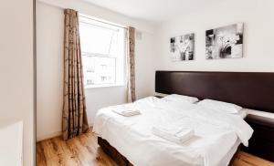 a bedroom with a bed with white sheets and a window at Parnell Apartments in Dublin
