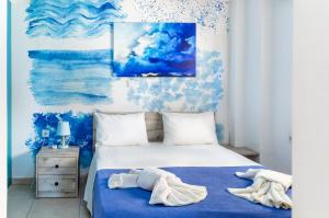 Un dormitorio con una cama azul y blanca con toallas. en Alternative Plan en Ierápetra