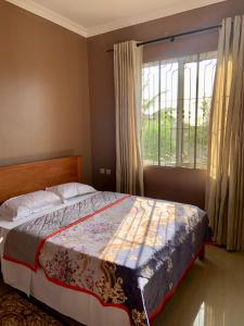 a bedroom with a bed and a large window at Dodoma, Tukae Inn in Dodoma