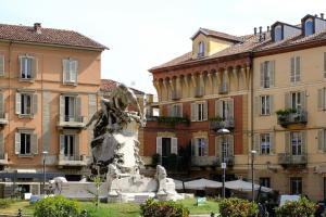 eine Statue mitten in einer Stadt mit Gebäuden in der Unterkunft Casa Medici in Asti