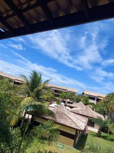 uma vista para um edifício com telhado e palmeiras em Apartamento em guarajuba 200m da praia em Camaçari
