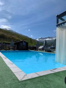 a large blue swimming pool with mountains in the background at Cosy Montagne in Valmeinier