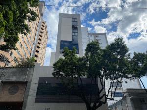 a tall building with a tree in front of it at Locking's Savassi 11 in Belo Horizonte
