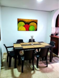 een eettafel met stoelen en een schilderij van fruit bij Espléndido apto completo en el centro de Pereira in Pereira