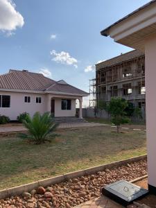 a house with a building in the background at Dodoma, Tukae Inn in Dodoma
