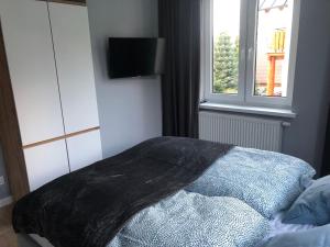 - un lit avec couverture dans une chambre avec fenêtre dans l'établissement Przystanek Karpacz, à Karpacz
