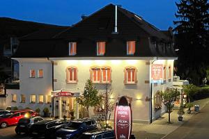 un gran edificio con coches estacionados frente a él en Hotel-Restaurant Axion, en Weil am Rhein