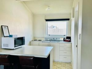 a kitchen with a microwave and a window at Parkside Motel and Apartments in New Plymouth