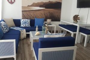 a living room with a blue couch and a table at Juan Dolio-2da Línea de Playa-Acceso Privado-Piscina-Área de Bbq-Gazebos-Jardines-Balcones-Wifi-Telecable-Netflix-Disney Plus-Campos de Gof-Excursiones-Plazas Comerciales-Minimarket-Restaurantes-Bares-Clubes de Playa in Guayacanes