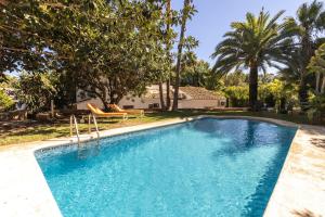 a swimming pool in a yard with trees and a house at Casa Algarrobo in Jávea