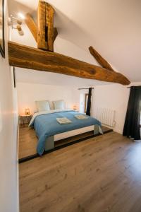 Schlafzimmer mit einem Bett mit blauer Bettwäsche und Holzböden in der Unterkunft La maison à Mimine in Le Pin-en-Mauges