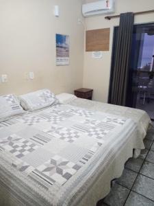 una camera con un letto con una trapunta sopra di Pousada Girassol a Rio das Ostras
