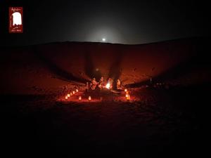 Eine Gruppe von Menschen, die nachts um ein Feuer herum sitzen in der Unterkunft Gite Agham Azegagh - Timimoun 
