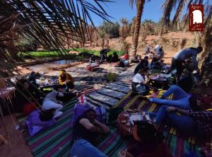 un gruppo di persone sedute sulla spiaggia a mangiare cibo di Gite Agham Azegagh - Timimoun 