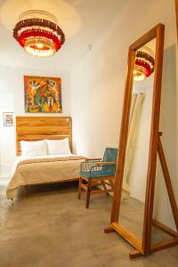 - une chambre avec un lit, un miroir et une chaise dans l'établissement NaNa Vida CDMX, à Mexico
