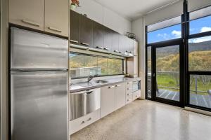 a kitchen with a stainless steel refrigerator and a window at Ecocrackenback 3 Sustainable chalet close to the slopes in Crackenback