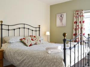 una camera da letto con letto, lenzuola e cuscini bianchi di The Farmhouse At Lane Foot a Tallentire