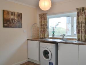 a kitchen with a washing machine and a window at The Farmhouse At Lane Foot in Tallentire