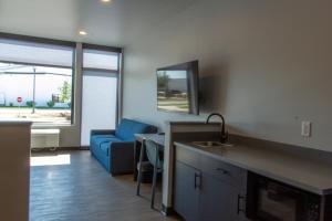 a living room with a blue couch and a kitchen at Watershed Hotel in Sheboygan