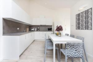a kitchen with white cabinets and a white table and chairs at Kinsky Garden Apartments and Suites in Prague