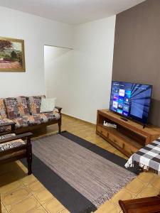 uma sala de estar com um sofá e uma televisão de ecrã plano em Casa aconchegante à 400m da Praia da Tartaruga - Ar condicionado - WIFI 450MB - Netflix - Cozinha Completa - Garagem em Rio das Ostras
