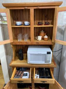a wooden cabinet with a microwave in it at Casa aconchegante à 400m da Praia da Tartaruga - Ar condicionado - WIFI 450MB - Netflix - Cozinha Completa - Garagem in Rio das Ostras