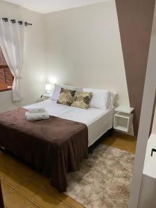 a bedroom with a white bed with a brown blanket at Casa aconchegante à 400m da Praia da Tartaruga - Ar condicionado - WIFI 450MB - Netflix - Cozinha Completa - Garagem in Rio das Ostras