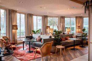 a living room with a couch and tables and windows at Best Western Plus l'Orée Paris Sud in Saulx-les-Chartreux