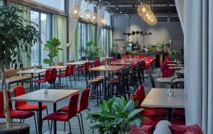 um restaurante com mesas, cadeiras vermelhas e plantas em Scandic Arlandastad em Arlanda