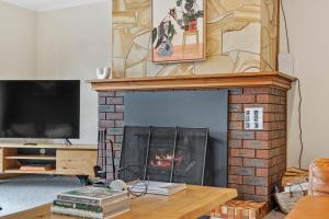 uma sala de estar com lareira e televisão em Lumeah Retreat Bruny Island em Adventure Bay