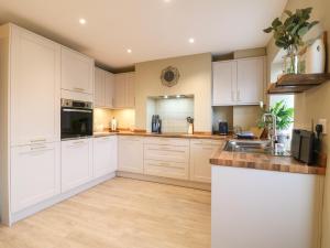 a kitchen with white cabinets and a sink at Red Robin Cottage in Chesterfield