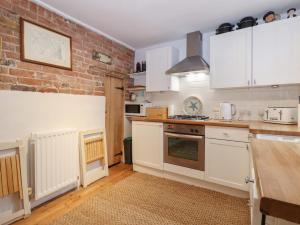 a kitchen with white cabinets and a brick wall at Kentish Knock in Deal