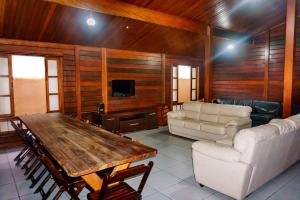 sala de estar con mesa, sillas y TV en Hostel Carcará, en Caraguatatuba