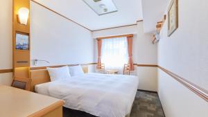Toyoko Inn Tokyo Akiba Asakusabashi-eki Higashi-guchi في طوكيو: غرفة صغيرة بها سرير أبيض وطاولة