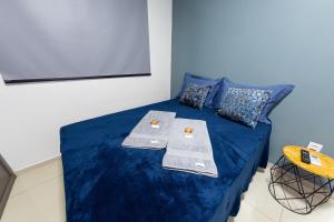 a room with a bed with blue sheets and a tv at Jahu Center Plaza Flats in Jaú