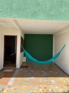 a green wall with a hammock in a room at Casa aconchegante à 400m da Praia da Tartaruga - Ar condicionado - WIFI 450MB - Netflix - Cozinha Completa - Garagem in Rio das Ostras