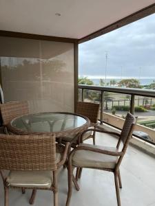 a glass table and chairs on a balcony with a view of the ocean at Flat na praia in Rio de Janeiro