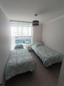 two beds sitting in a room with a window at Arriendo Depto. Diario Coquimbo in Coquimbo
