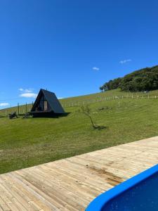 ein schwarzes Zelt auf einem Feld mit einer Holzterrasse in der Unterkunft Hotel Guerra - Pousada Montebelo in Jaguaruna