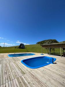 una piscina azul en una terraza de madera con mesa de picnic en Hotel Guerra - Pousada Montebelo, en Jaguaruna