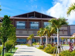a building with palm trees in front of it at Crown Hotel Okinawa Annex in Okinawa City