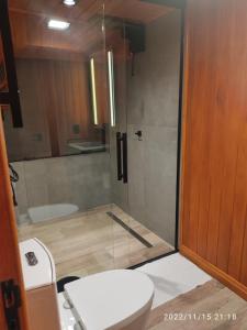 a bathroom with a toilet and a glass shower at Grandi Pousada Sports - Sambaqui - Chalé Jurerê, Chalé da Mole e 3 Cabanas in Florianópolis